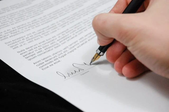 A hand signing a document with a fountain pen