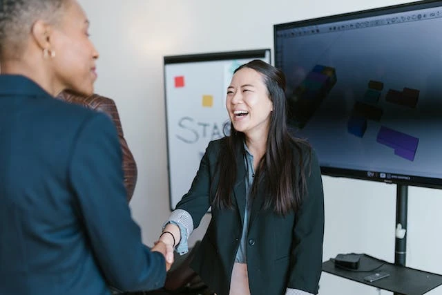 Two people smiling and shaking hands with each other