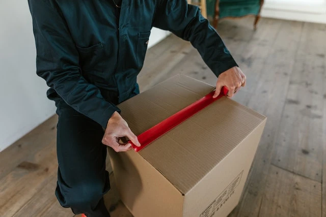 Close up of hands taping a moving box closed