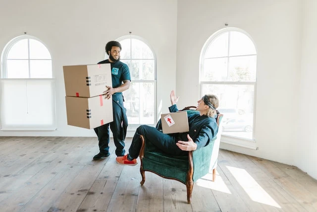 Two movers in jumpsuits holding cardboard boxes