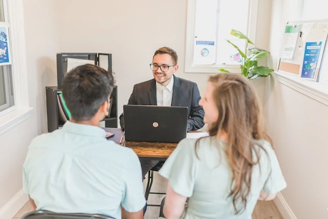 Person sitting behind a desk talking to two people