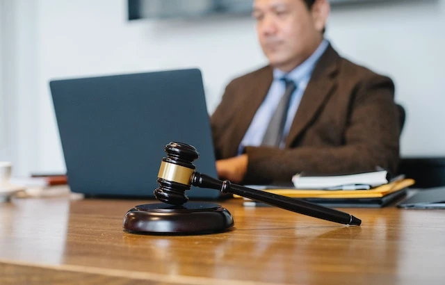 A lawyer working on their laptop at their desk, a gavel is in the foreground
