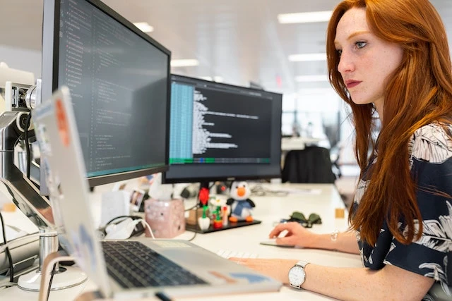 A software engineer with long red hair working on coding a property management software