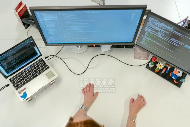 Software engineer working on three screens