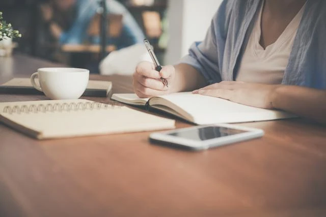 Person writing in a notebook about security deposits at a table