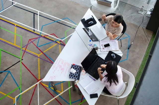 Overhead of two people working on laptops together at a table