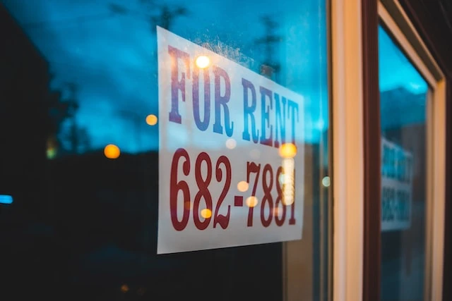 Red and white for rent sign in a window of a real estate property