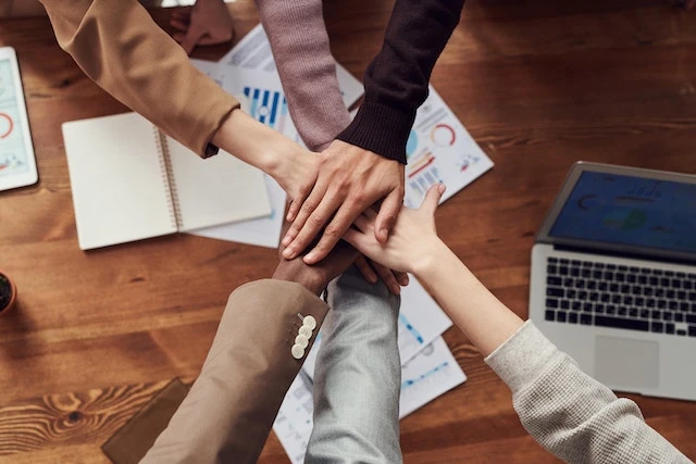 Six people’s hands stacked on top of each other