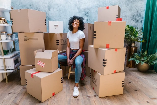 Smiling person surrounded by piles of cardboard moving boxes