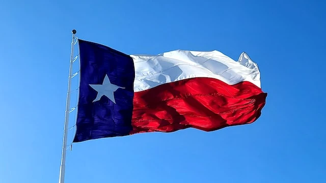 Texas state flag blowing in the wind against a blue sky