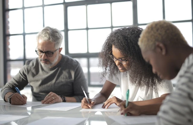 Three focused people comparing notes at a conference table