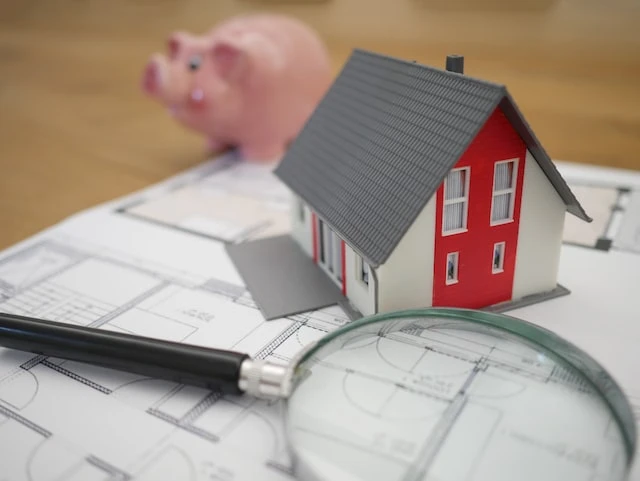 Small house, pig, and magnifying glass on top of a floor plan