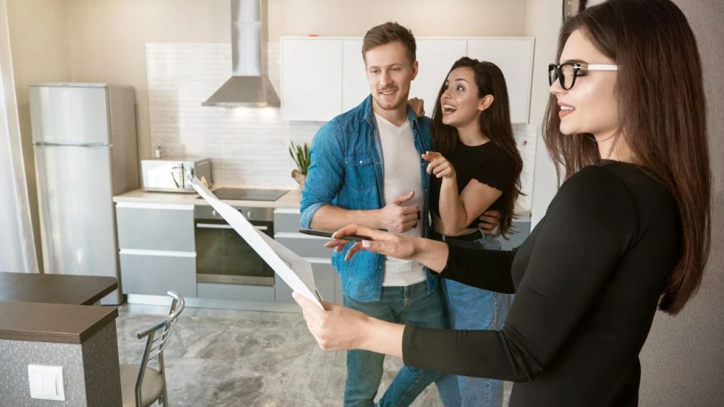 Two excited people looking at plans in a kitchen with their property manager