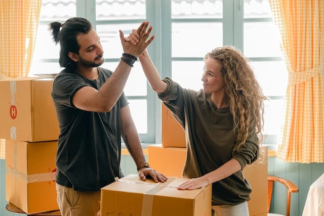 two happy renters high-fiving over moving boxes