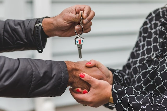 Person holding a key over their other hand being clasped by another person’s hands