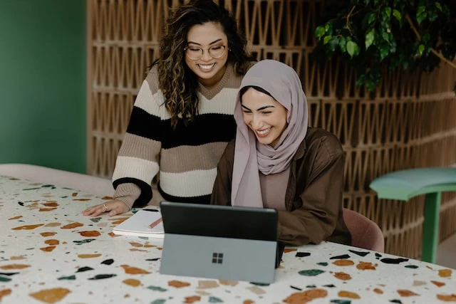 Two people smiling and looking at a laptop screen