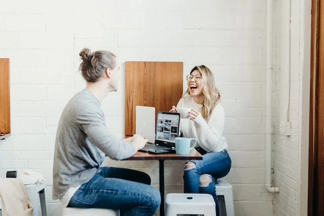 Two real estate agents smiling and talking at a table