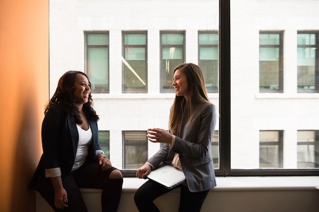 Two real estate agents talking in front of a large window