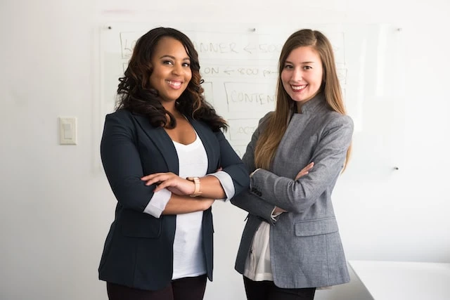 Two smiling property managers in suits crossing their arms next to each other