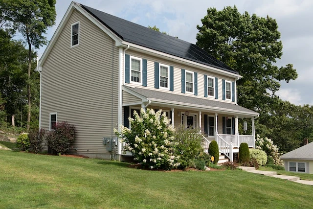 White-two-story-house-with-blue-shutters-and-a-large-green-lawn