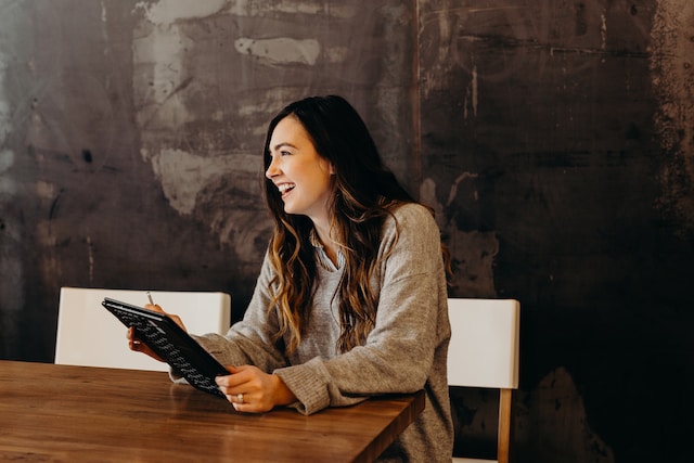 Smiling person sitting at a table working on a tablet