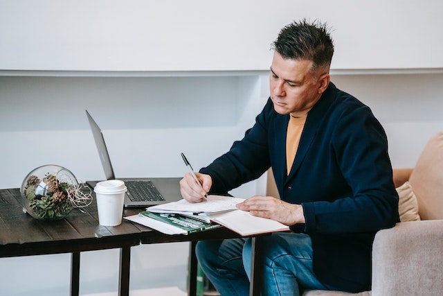 Person writing in a notebook at a cafe table