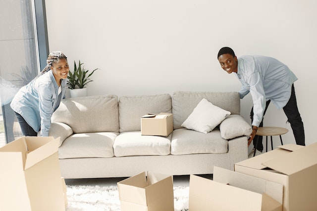 two people smiling and lifting a couch