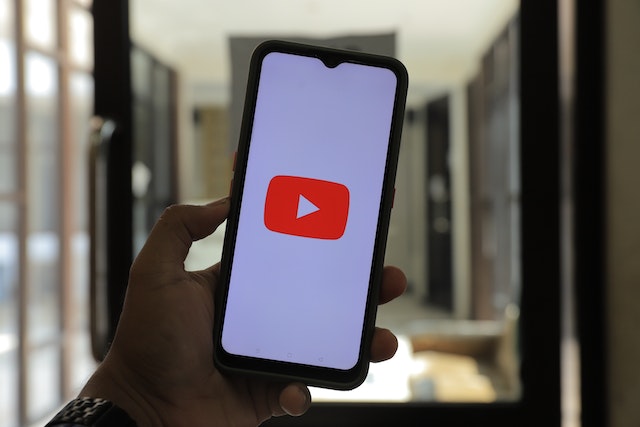 Person Holding a Black iphone with the youtube logo on a white background