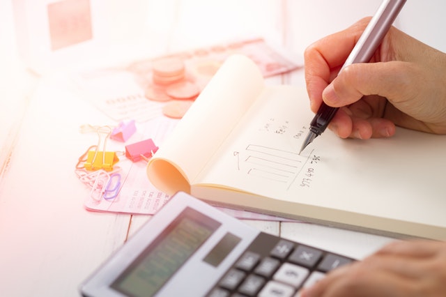 Close up of someone using a calculator and notebook to create a financial plan