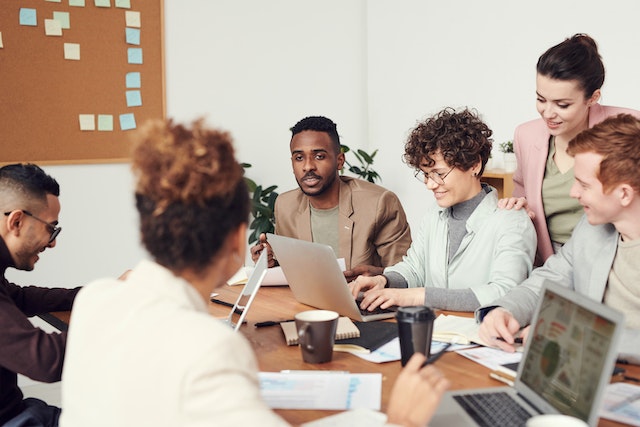 Group of six people working together around a table in an office