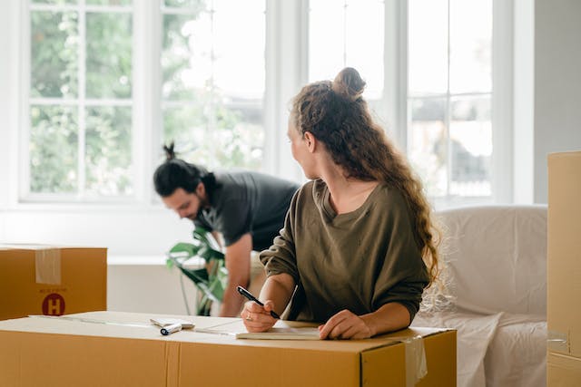 Two people writing on moving boxes