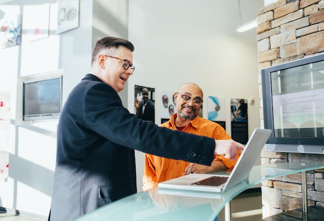 Two men smiling and looking at a laptop screen