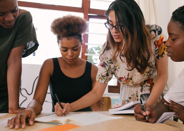 Four people working over a table together writer a letter