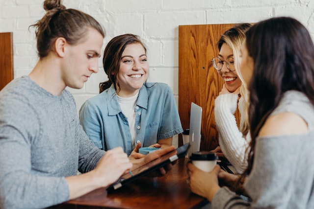 Four people sitting at a table smiling and talking