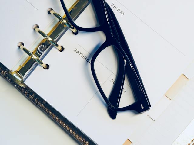 Black glasses sitting on top of a weekly planner