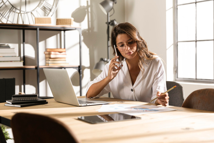 Property manager in a white blouse working at her desk while talking on the phone