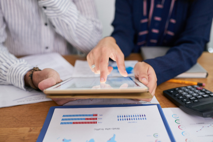 Close up of two peoples hands reviewing graphs on a tablet