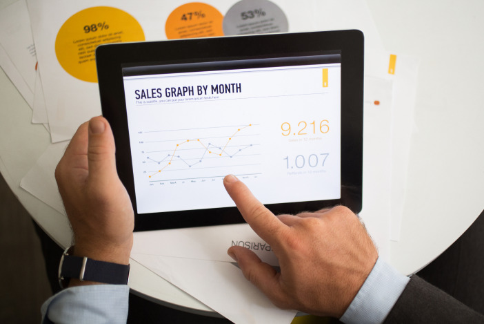 Someone holding a tablet and pointing at it with their finger