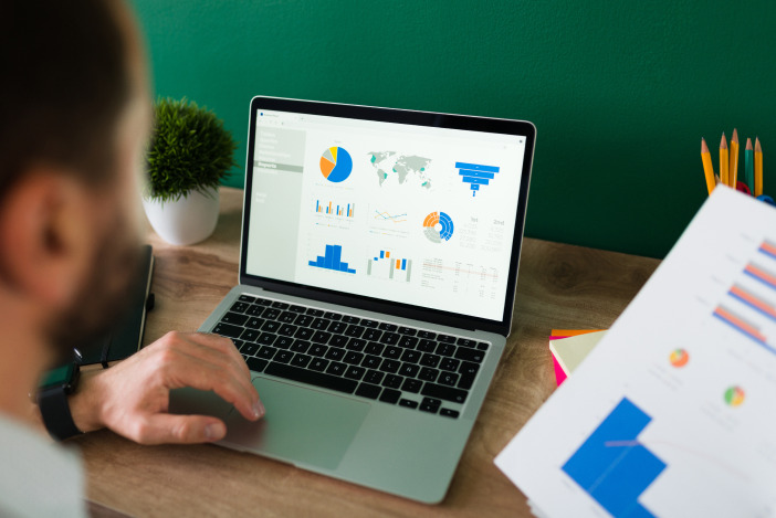 Person looking at various graphs on their laptop in front of them