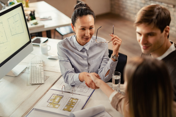 Three people working at a desk together looking over floor plans of a house