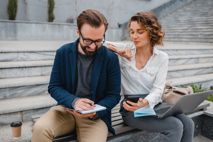 Two people looking at notes on concrete steps