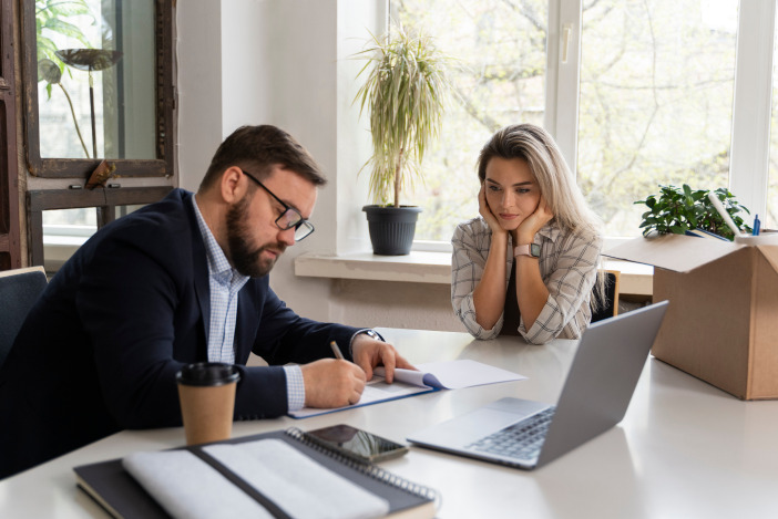Two people working at a desk together, reviewing a document in front of a laptop
