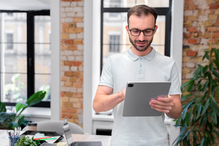 A man standing in a living room holding a large tablet