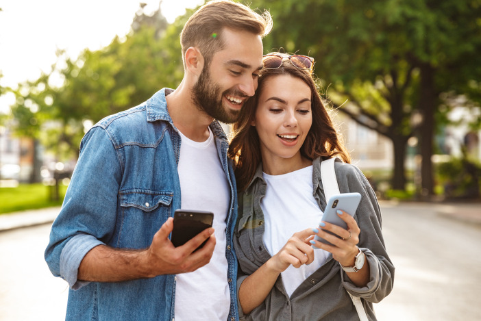 A smiling man and woman looking at something on the smartphone the woman is holding