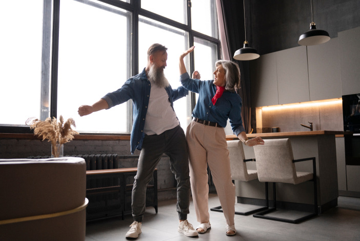 Two older people with grey hair dancing in an office