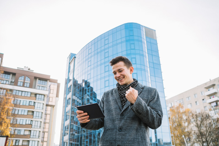 Man standing out side in a plaid coat looking at a tablet