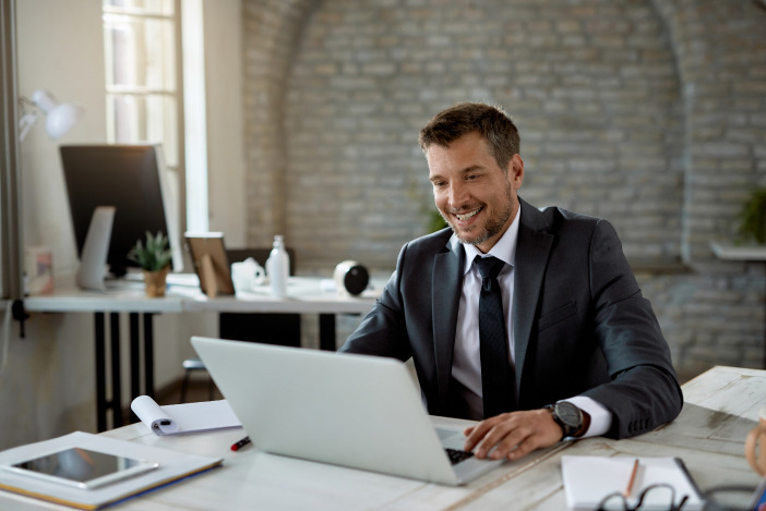 Smiling man in a suit working on a laptop