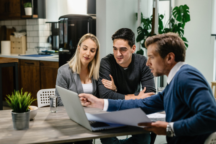 Three professionals working around a laptop together
