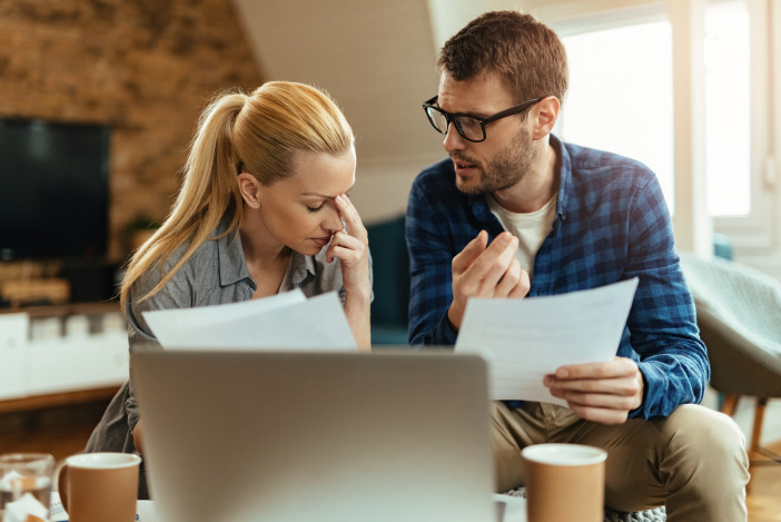 Two real estate professionals speaking next to each other, both are holding papers in their hands
